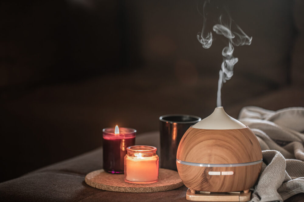 Oil diffuser on blurred space near burning candles. Aromatherapy and health