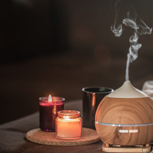 Oil diffuser on blurred space near burning candles. Aromatherapy and health
